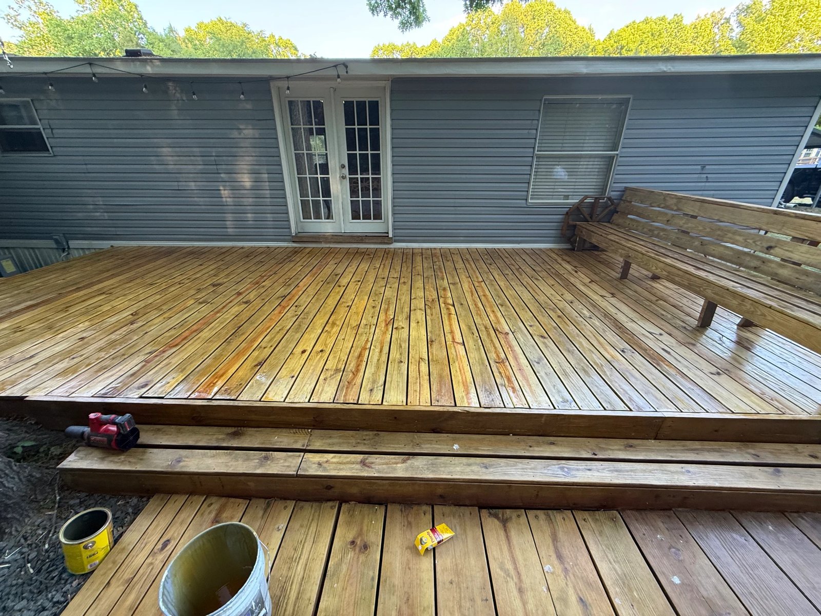 Freshly stained backyard deck with built-in bench beside gray siding