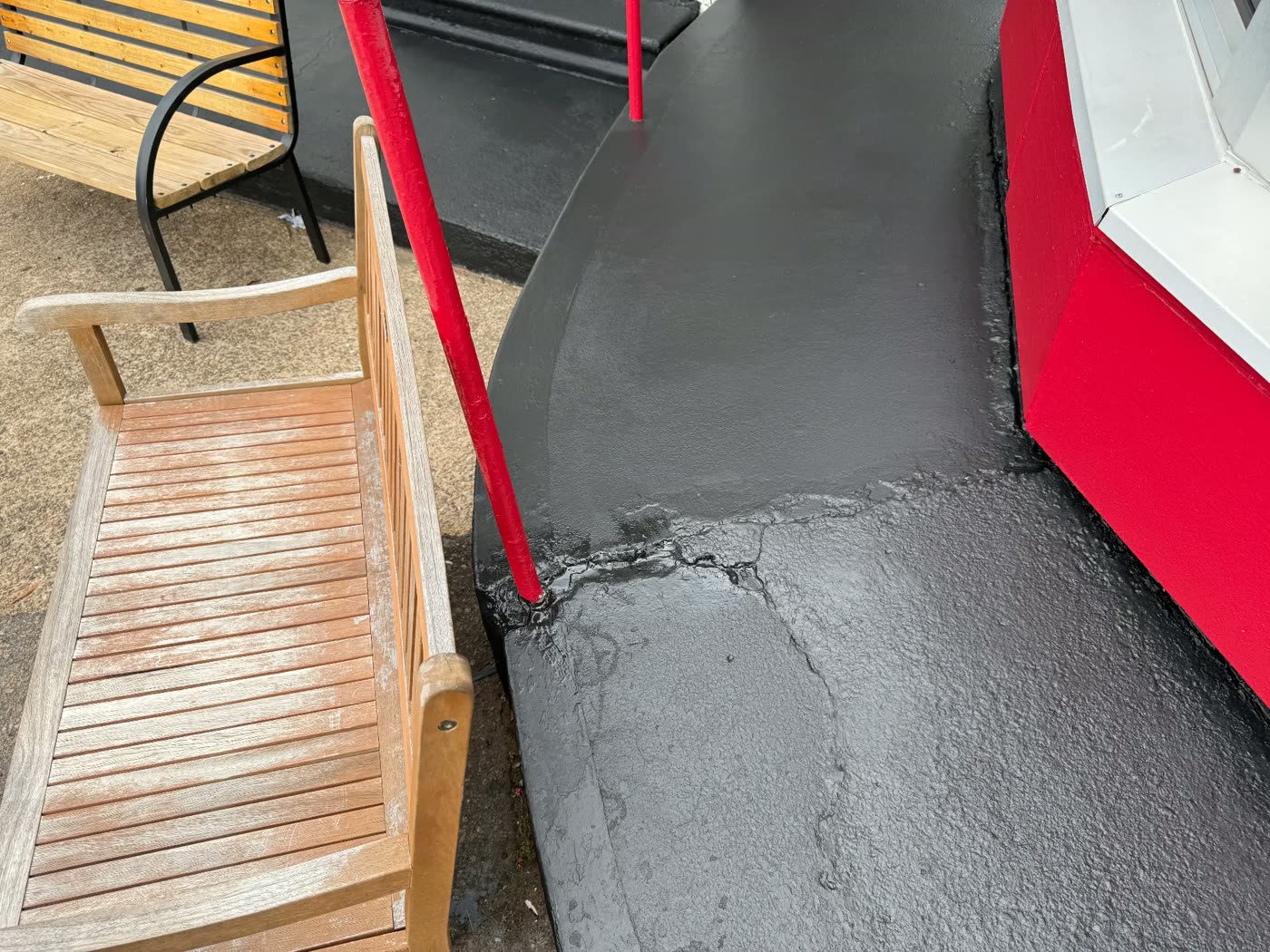 Sidewalk and curb coated in durable dark gray with red railings