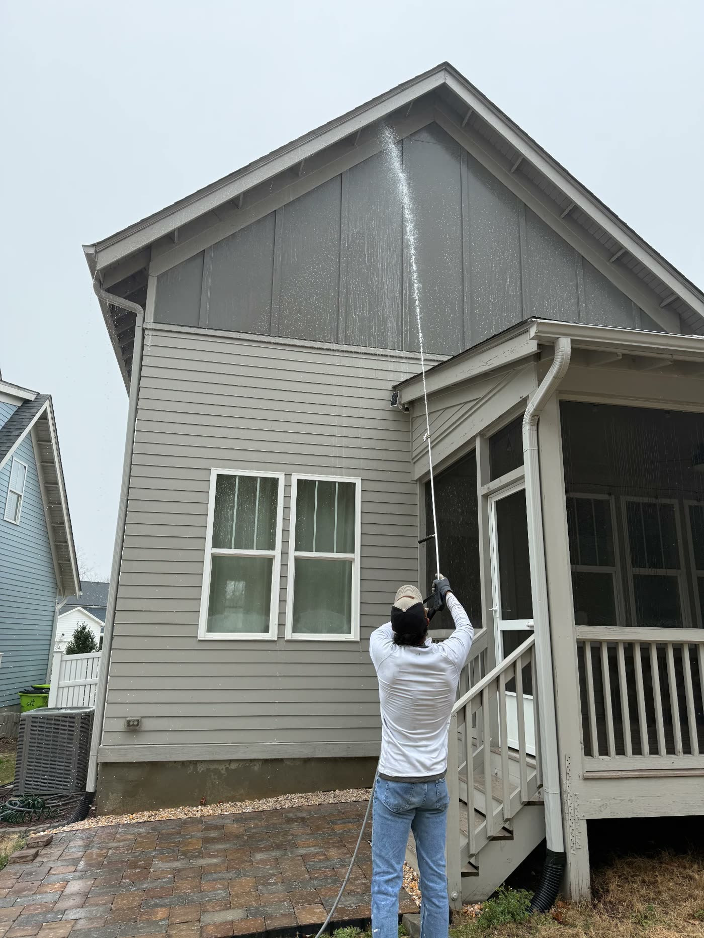 Soft washing a home's upper gable and siding before painting