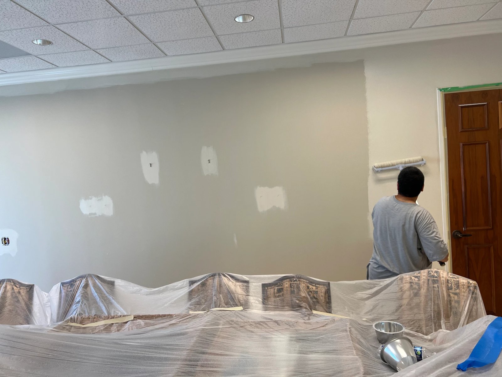 Painter rolling a smooth finish coat on a large office wall