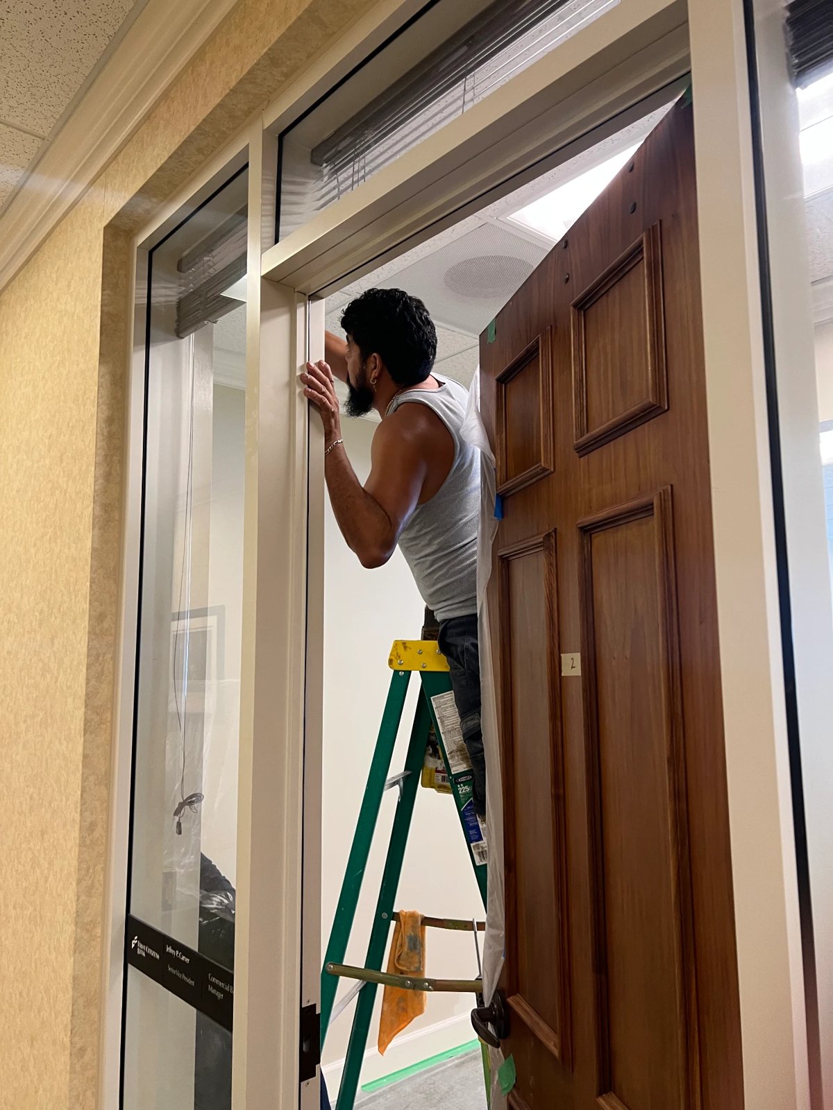 Painter on a ladder detailing an office door frame