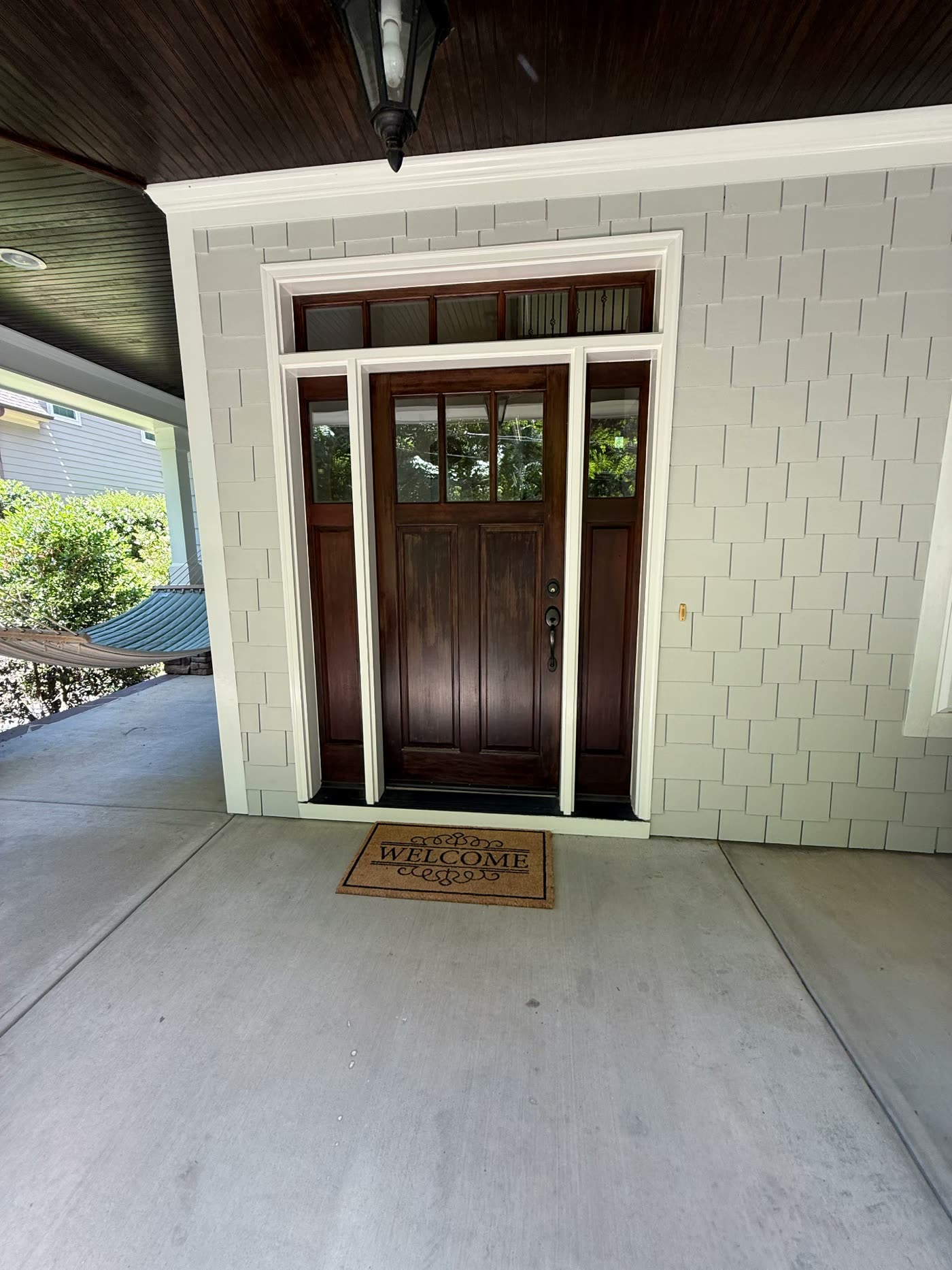 Refinished craftsman front door with crisp white trim and painted shake siding