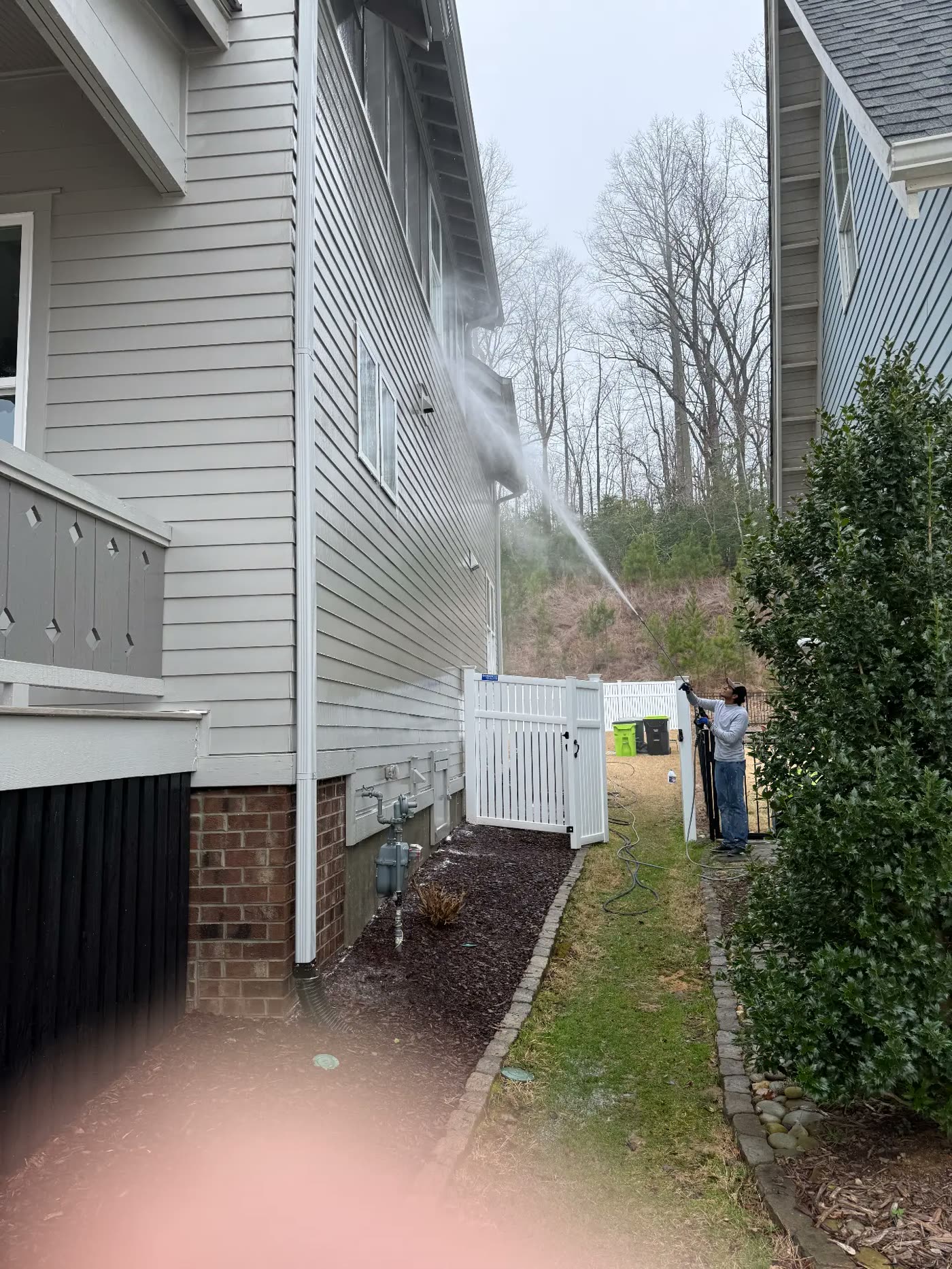 Pressure washing the side elevation of a home to prep for exterior paint