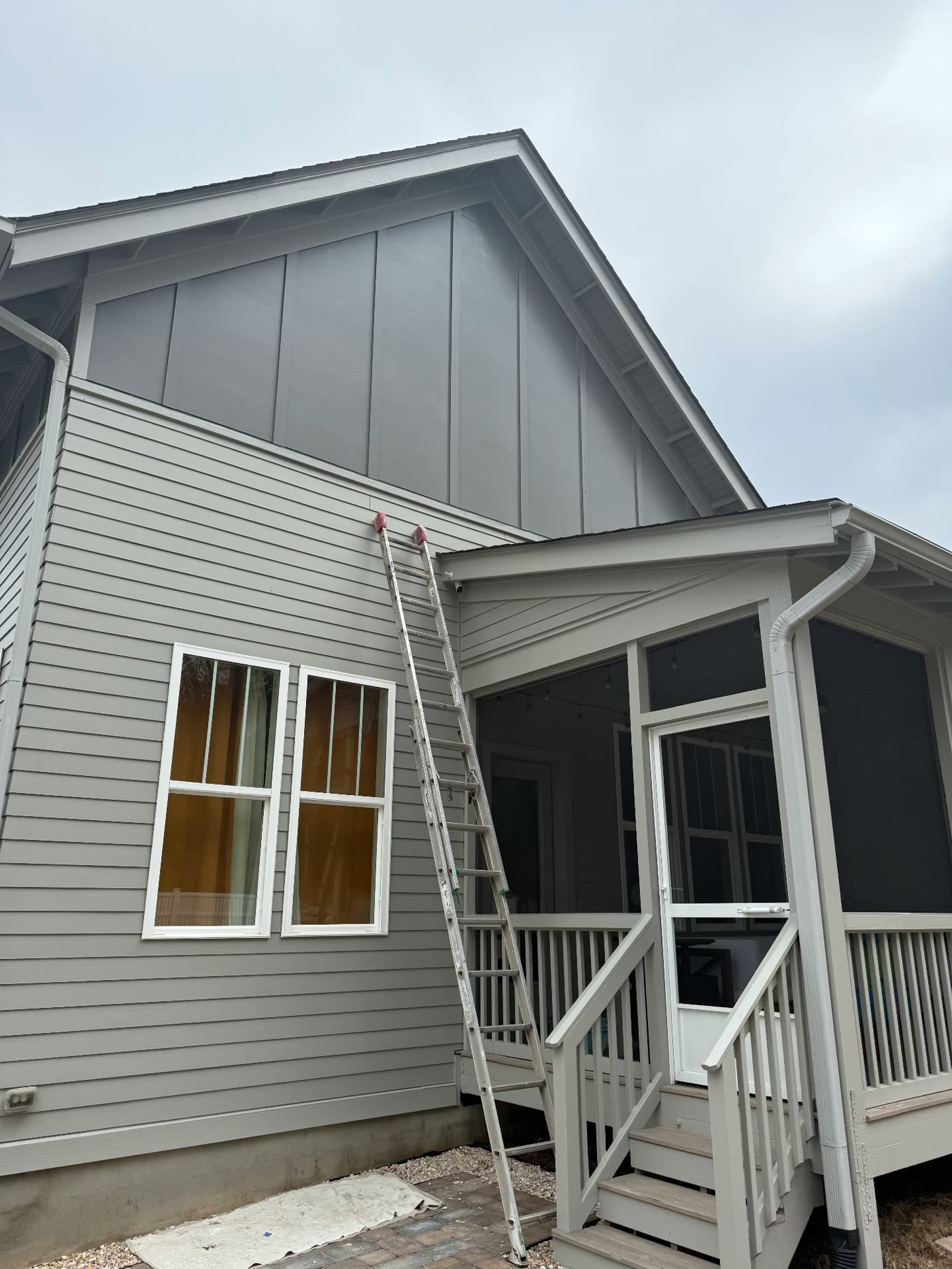 Gray board-and-batten gable and siding freshly repainted with white trim