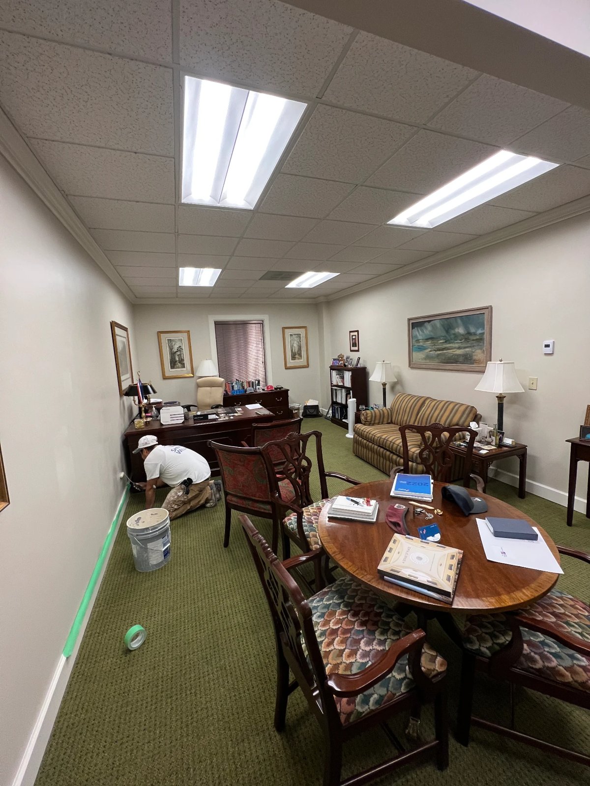Painter cutting in baseboards during an executive office repaint