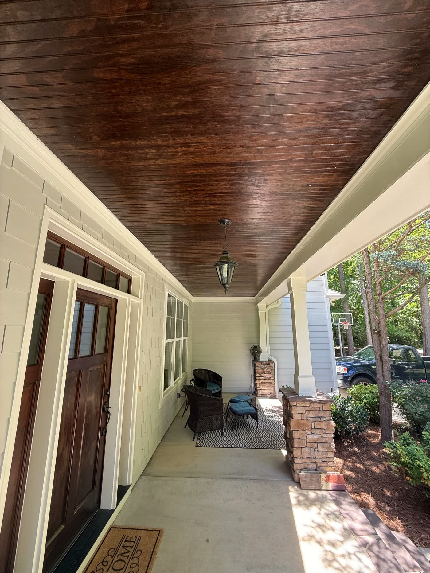 Covered porch with richly stained wood ceiling and painted trim