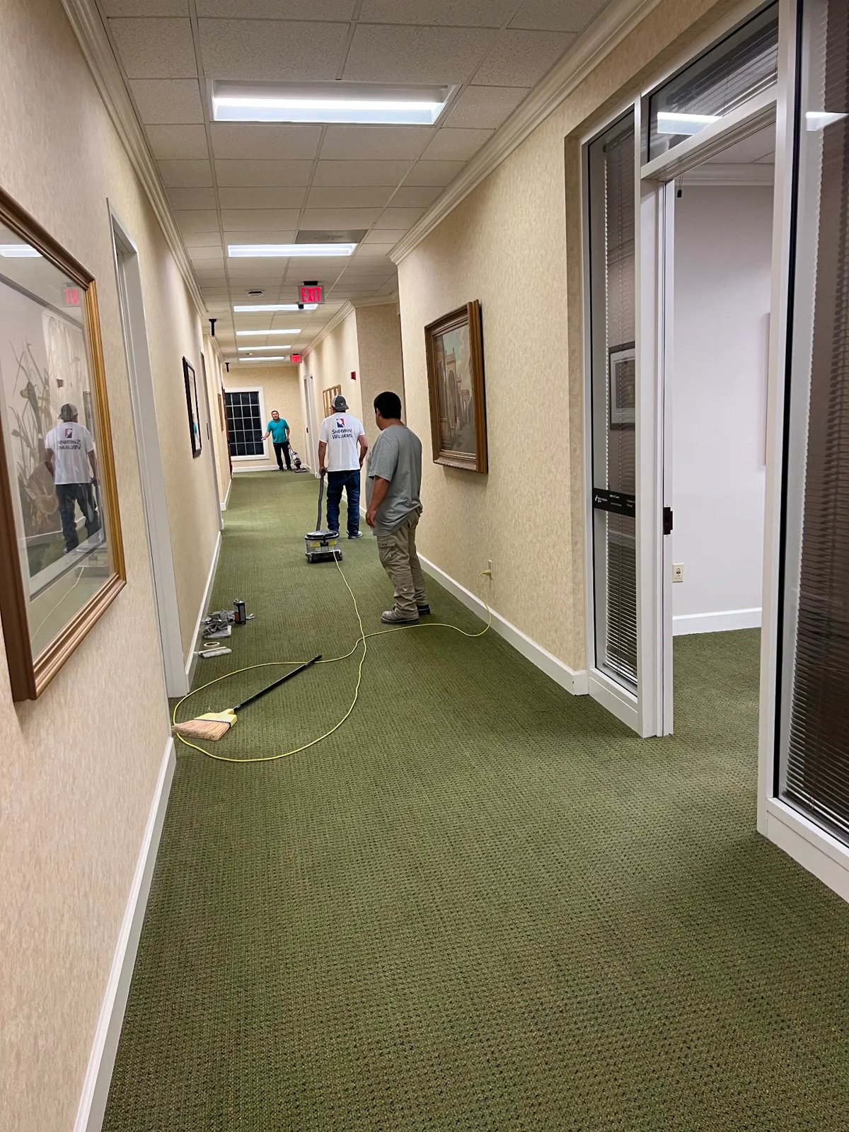Crew refreshing walls and trim along a commercial office corridor